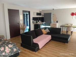 a living room with a black couch and a kitchen at Telhadosolitario in São Pedro da Cova