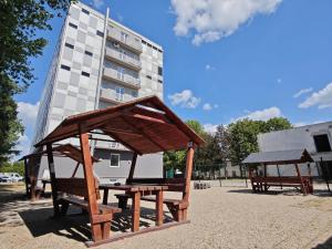 two benches in a park with a building in the background at Hotel Slobi in Štúrovo