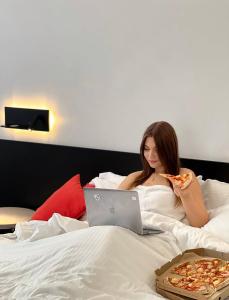 a woman laying in bed eating a slice of pizza at Atmosfera Hotel in Odesa