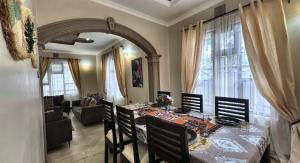 a dining room with a table with chairs and an archway at Jubilant Experience Homes Arusha in Arusha