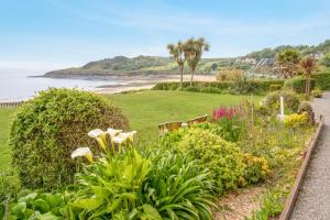 a garden with flowers and the beach in the background at 2 Bed in Mumbles oc-hh141 in Newton