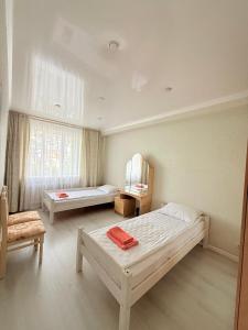 a room with two beds and a chair and a window at Jaily in Astana