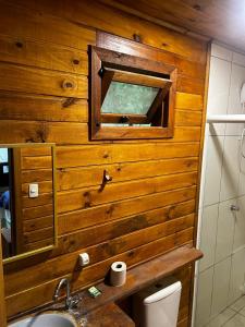 a bathroom with a wooden wall with a mirror and a sink at Hotel Pirâmides Sagradas in Grão Pará
