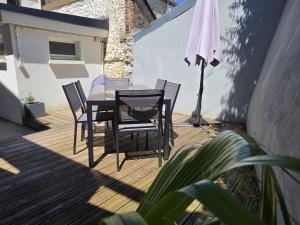 a table and chairs on a deck with an umbrella at La Caloge in Fécamp