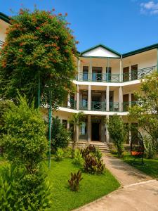an apartment building with a tree with red flowers at Hotel Kopala Ureki in Ureki