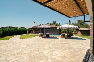 a patio with umbrellas and chairs and a pool at Villa giannis in Vitalades