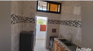 a kitchen with a sink and a door to a room at Perles de ngaparou in Saly Portudal