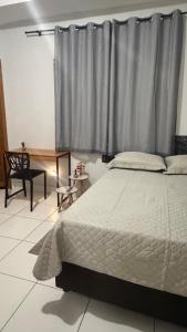 a bedroom with a bed and a chair and a window at Sobrado Tropical a 1 Km da faculdade Unic e UFMT in Cuiabá