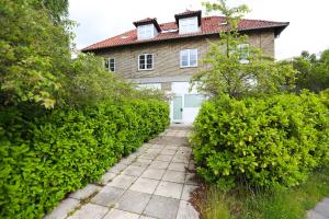 a house with green bushes in front of a walkway at Exclusive 1 bedroom apartment in Copenhagen