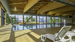 a swimming pool with two white chairs in a house at VTF Le Dou De La Ramaz in Montalbert