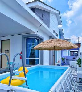 a swimming pool with an umbrella and a yellow inflatable at Santorini Vibes Penang - Tasek Gelugor in Kampong Selamat