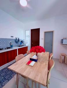 a dining room table with a vase of red flowers on it at Santorini Vibes Penang - Tasek Gelugor in Kampong Selamat