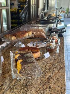 a counter with different types of pastries and bread at Alfa Mar Pousada in Abraão