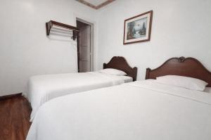 two beds in a room with white sheets at Hotel Grer By Chat Noir in Cuenca