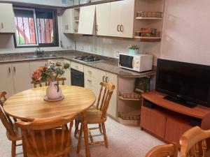 a kitchen with a wooden table and a television at Habitación privada con zonas compartidas in Castellbisbal
