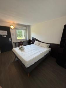 a bedroom with a large bed with white sheets at Couett' Hotel Rumilly in Rumilly +3 photos