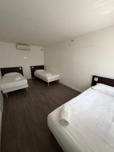 a hotel room with two beds and two tables at Couett' Hotel Rumilly in Rumilly