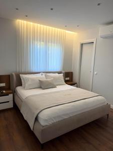 a bedroom with a large white bed with a window at AMAD Aparthotel in Sarandë +65 photos