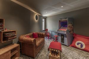 a living room with a couch and a pinball machine at Canopee 206 - by Care Concierge in Saint-Gervais-les-Bains