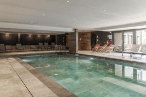 a large swimming pool with chairs and a table at Canopee 206 - by Care Concierge in Saint-Gervais-les-Bains