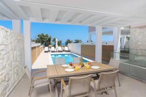 a dining area with a table and chairs and a pool at The Serata Villas 2 in Hanioti