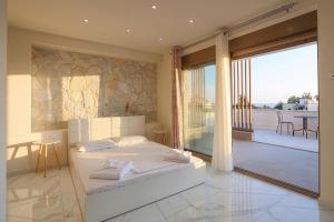a bedroom with a white bed and a balcony at The Serata Villas 2 in Hanioti