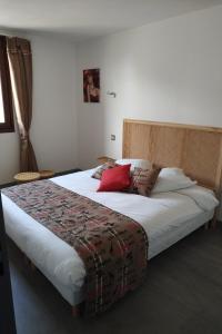a bedroom with a large bed with red pillows at Hôtel Restaurant Ardesia in Peyrelevade