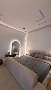 a white bedroom with a large bed with a couch at استديو فندقي دخول ذكي عائلي مريح in Al Ahsa