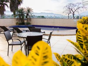 a patio with tables and chairs and a swimming pool at Ville de Montagne Hotel in Brumadinho