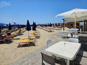 a beach with lounge chairs and tables and umbrellas at Casa Caribe - Piscina, Spiaggia e Parcheggio inclusi! GRATIS in Sanremo