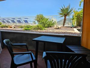 a table and chairs on a balcony with a view of a palm tree at Casa Caribe - Piscina, Spiaggia e Parcheggio inclusi! GRATIS in Sanremo