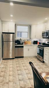 a kitchen with white cabinets and a stainless steel refrigerator at Hamilton Central 3BR Family House in Hamilton +17 photos