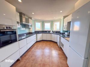 a large kitchen with white cabinets and a tile floor at Beachfront Apartment - Sea View - COU02 in Ayamonte