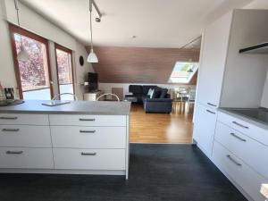 a kitchen with white cabinets and a living room at Ferienwohnung am Keltenwall in Jestetten
