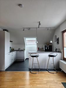 a kitchen with a counter and two stools in it at Ferienwohnung am Keltenwall in Jestetten
