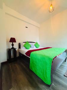 a bedroom with a bed with a green comforter at The Urban Hideout in Nuwara Eliya