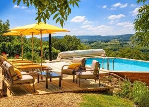a wooden deck with chairs and an umbrella next to a swimming pool at Villa Piscine et Jaccuzzi - Vue Panoramique in Juillac