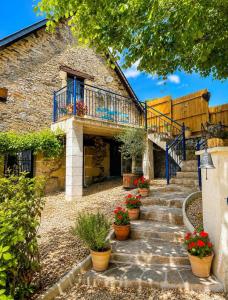 a stone house with a staircase and flower pots at Villa Piscine et Jaccuzzi - Vue Panoramique in Juillac