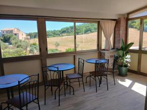 a room with four tables and chairs and windows at Cindy Cottage Holiday Home in Giuncarico
