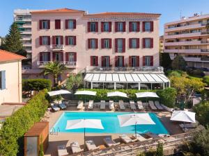 a hotel with a swimming pool with chairs and umbrellas at Best Western Hôtel des Orangers Cannes in Cannes