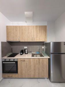 a kitchen with wooden cabinets and a stainless steel refrigerator at Royal Vinea Suites in Elevtheraí