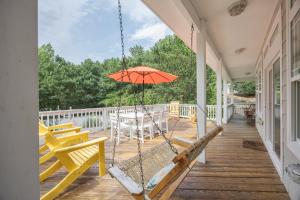 a porch with a swing and an orange umbrella at 4096 - Cake by the Ocean in Duck
