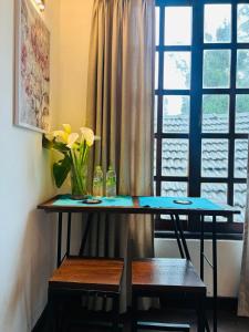 a table with a vase of flowers and a window at The Urban Hideout in Nuwara Eliya