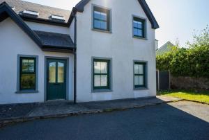 a white house with a green door at Old Rectory House - Waterville in Waterville