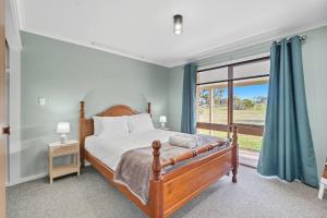 a bedroom with a bed and a large window at Wildlife, Waves Getaway in Acton Park