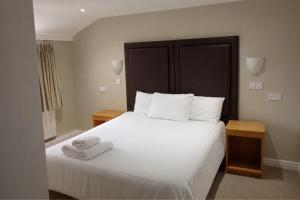 a bedroom with a large white bed with towels on it at Wakefield Limes Lodge in Wakefield