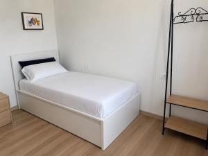 a small bedroom with a white bed and a wooden floor at Casa Candola in Noya +1 photo