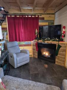 a living room with a chair and a fireplace at Cozy Christmas Cabin in North Pole