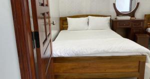 a bedroom with a bed with white sheets and a mirror at Nhà Nghỉ Motel NGỌC KIM NGÂN in Quy Nhon