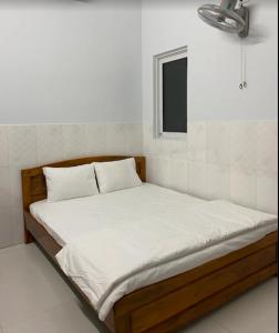 a bed with white sheets in a room at Nhà Nghỉ Motel NGỌC KIM NGÂN in Quy Nhon